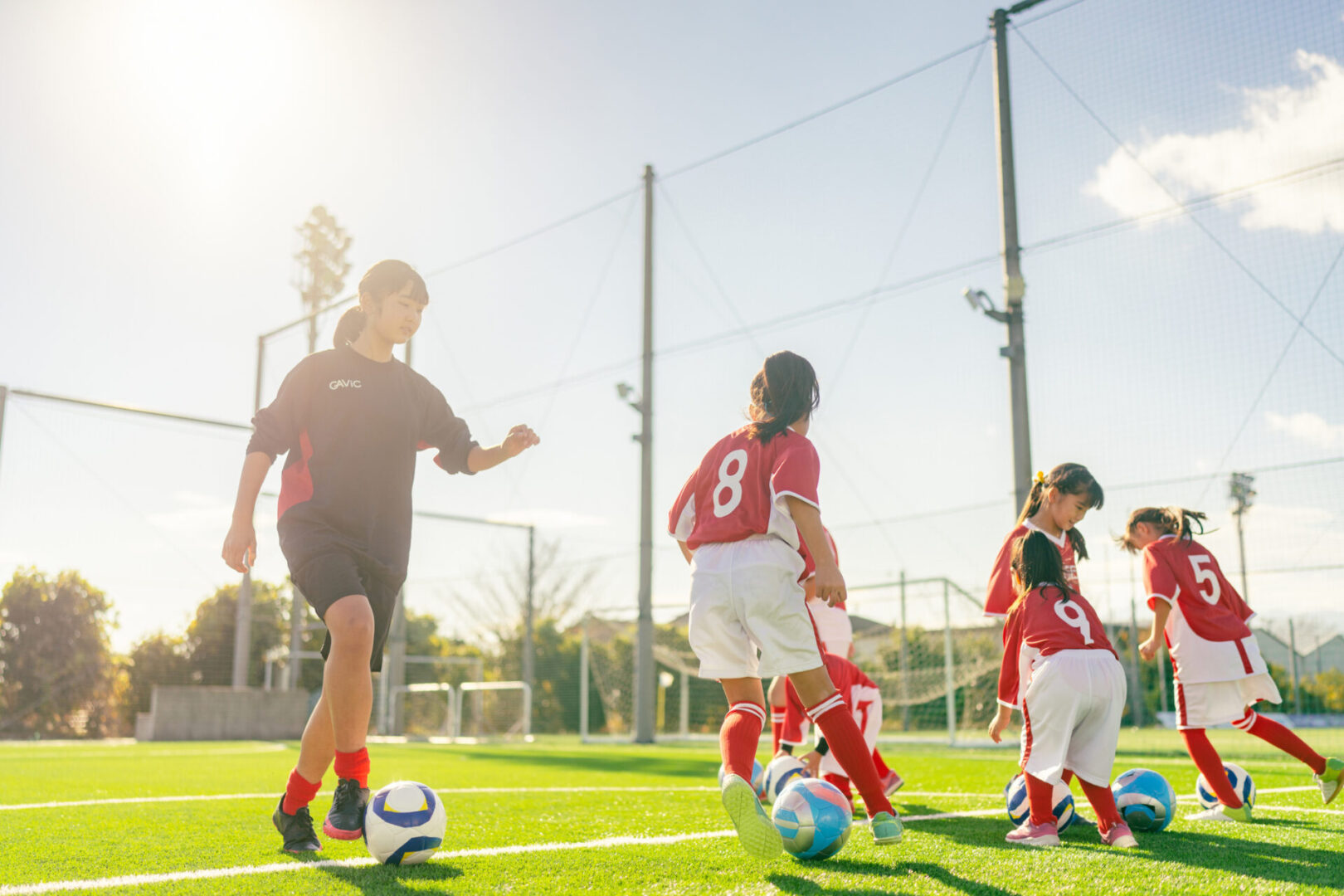 Children playing soccer on a sunny field.