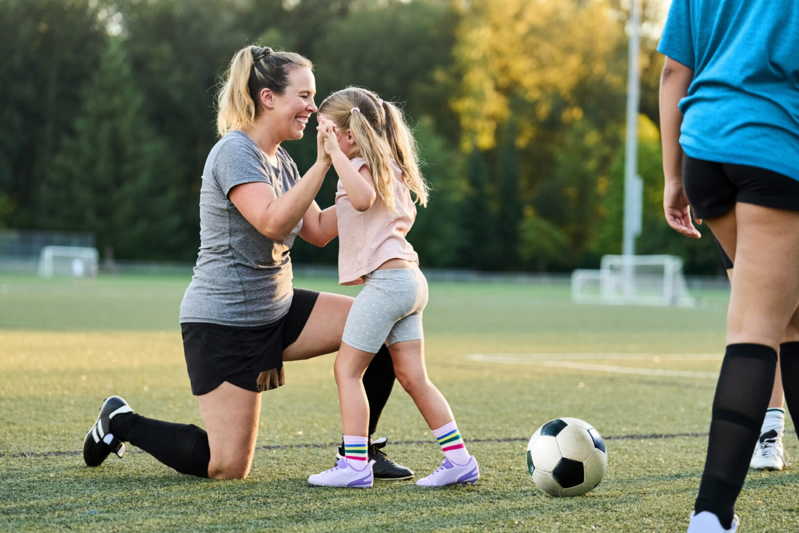 Woman and child on soccer field, bonding moment.