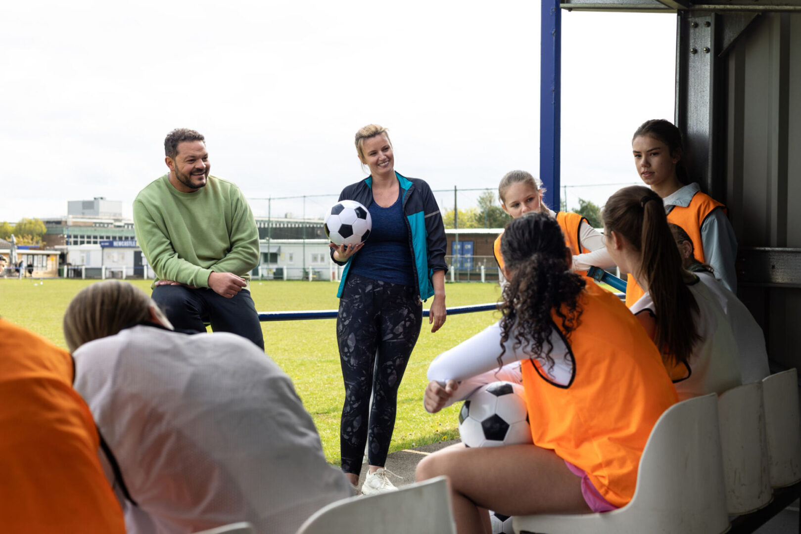 Coaches and girls' soccer team on sideline.